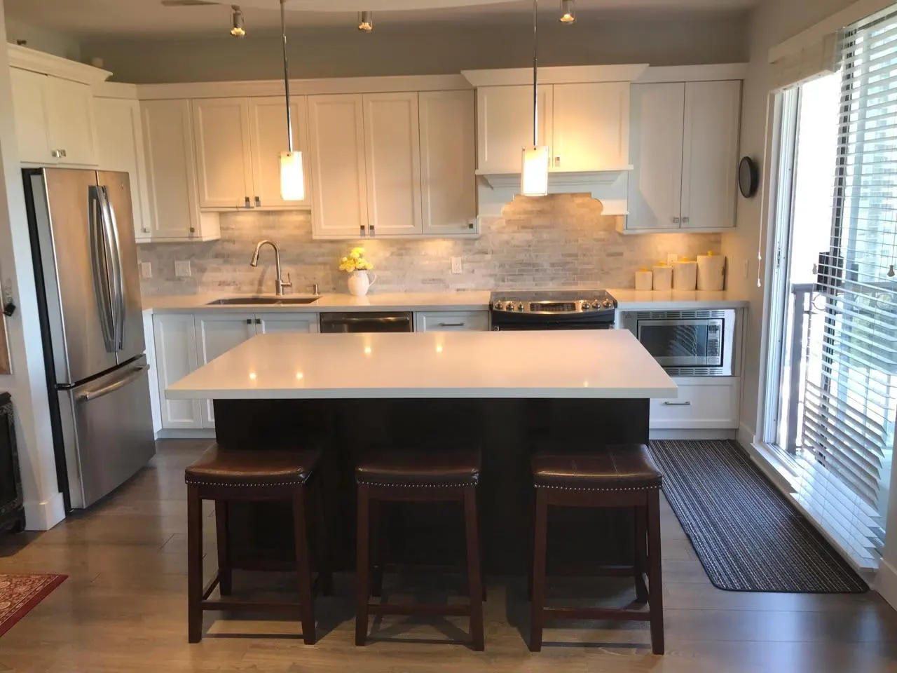 Finished kitchen with a dark wood island, stacked-stone backsplash and hardwood flooring