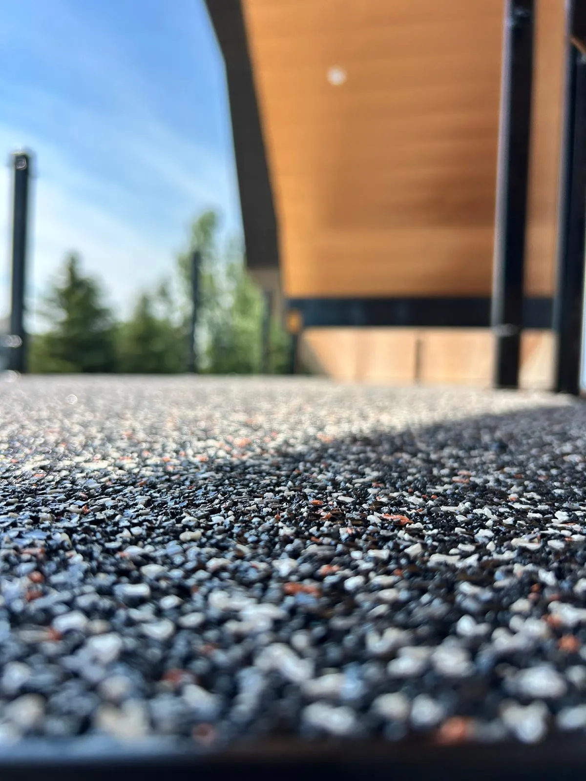 Ground-level macro shot of the speckled black, white, and orange rubber texture on a finished exterior landing